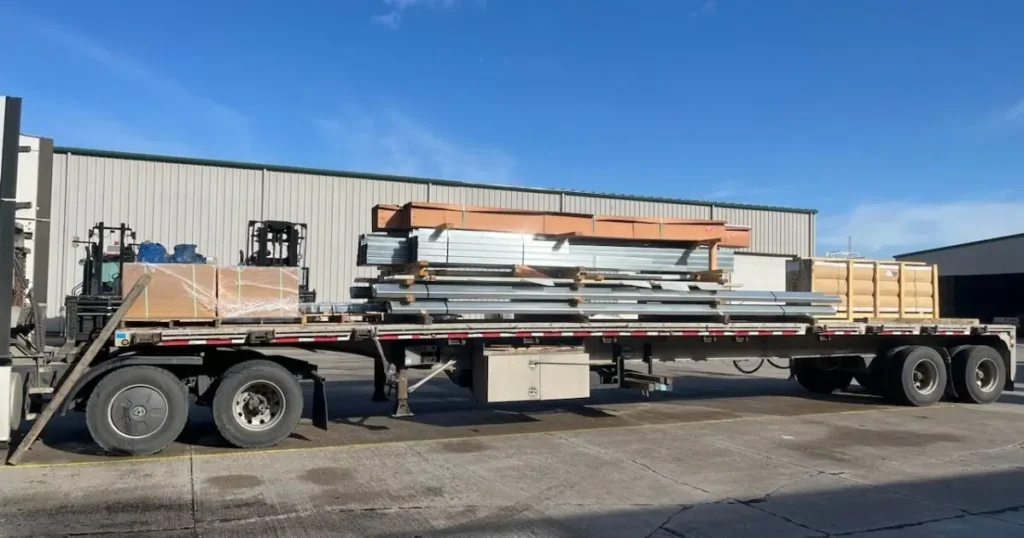 Flatbed truck loaded with Tower Steel Buildings Canadian-made steel components at Ontario manufacturing facility