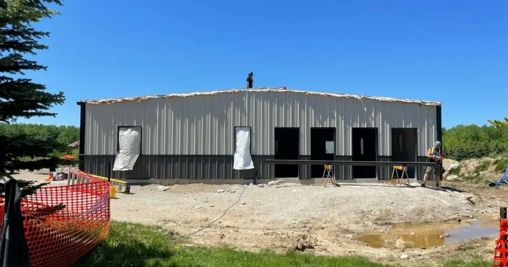 Ontario steel building under construction by Tower Steel Buildings with crew installing exterior cladding and insulation