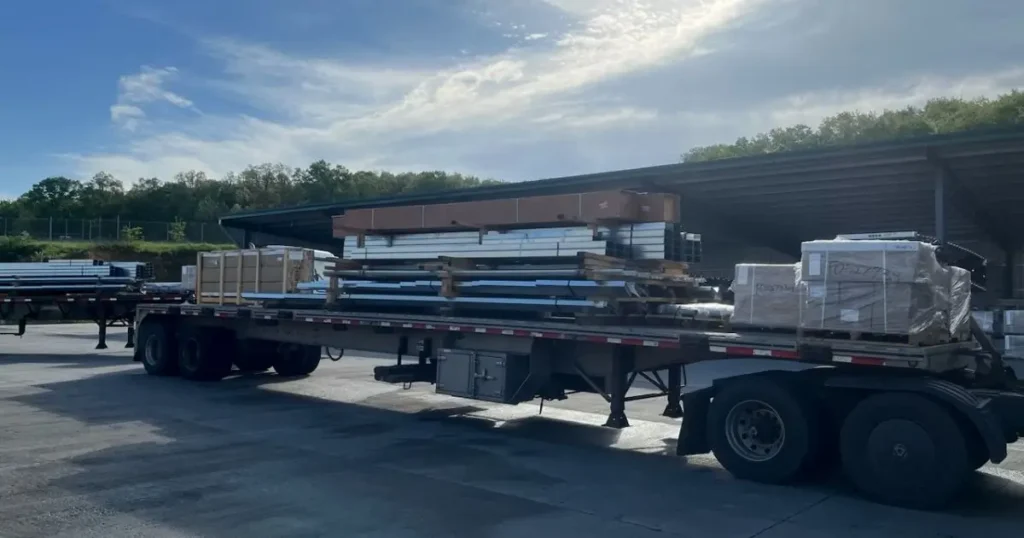 Flatbed truck loaded with prefab Tower Steel Buildings components ready for delivery to a construction site in Ontario