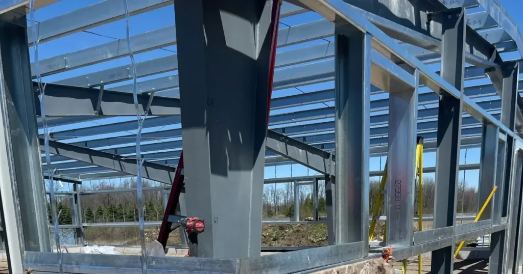Steel building under construction in Ontario showing insulation installation around wall base for energy efficiency and condensation control