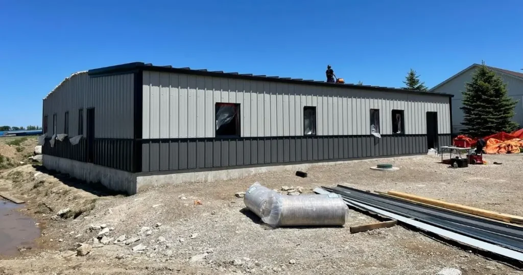 Modern pre-engineered steel building in Ontario with dual-tone grey panels and concrete foundation under clear blue sky
