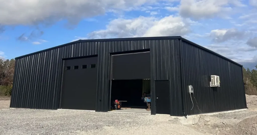 Modern prefabricated steel building in Ontario with black wall panels and large overhead doors under blue sky