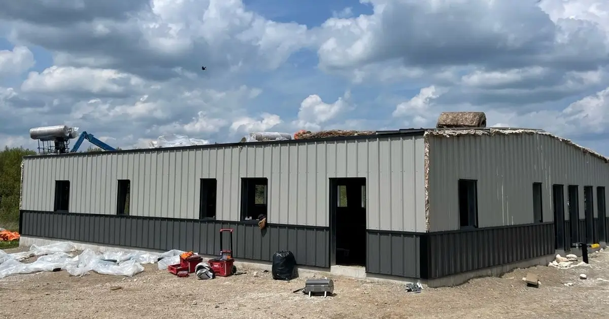 Steel building under construction in Ontario with two-tone grey wall panels and clear blue sky