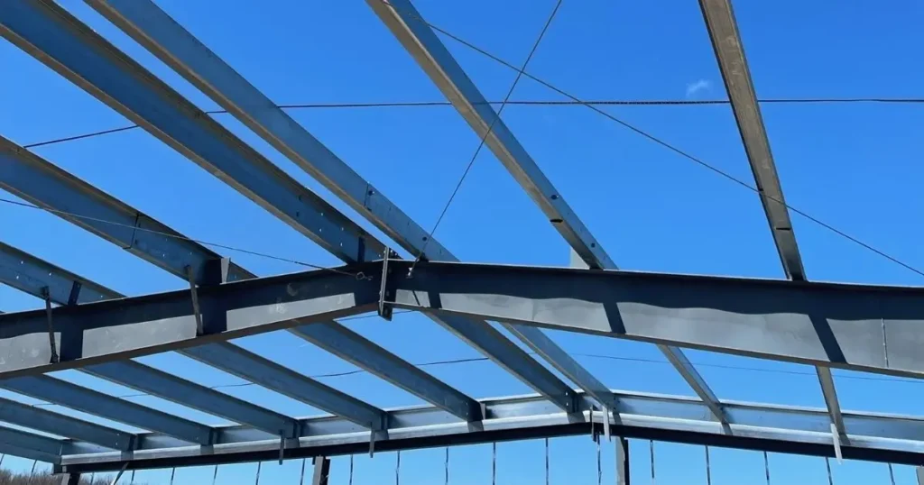 Close-up view of steel frame roof structure in Ontario under clear blue sky showing precision alignment and cross bracing