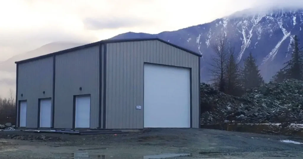 Structural steel building in Ontario with light grey wall panels and large roll-up doors set against mountain backdrop