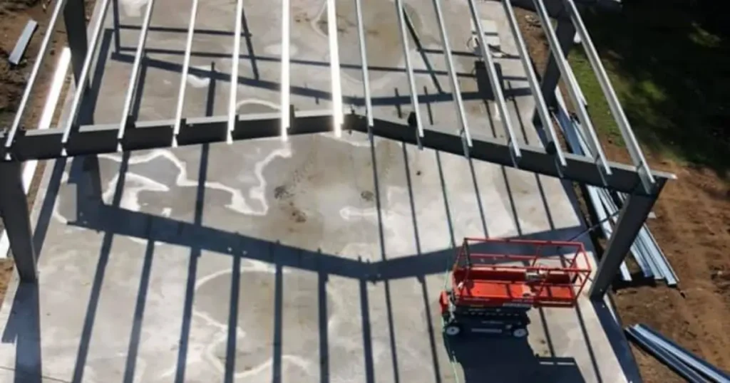 Aerial view of Tower Steel Buildings crew assembling a steel structure frame on concrete foundation in Ontario