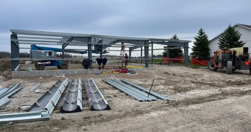 Steel building framework under construction in Ontario by Tower Steel Buildings showing site preparation and foundation setup