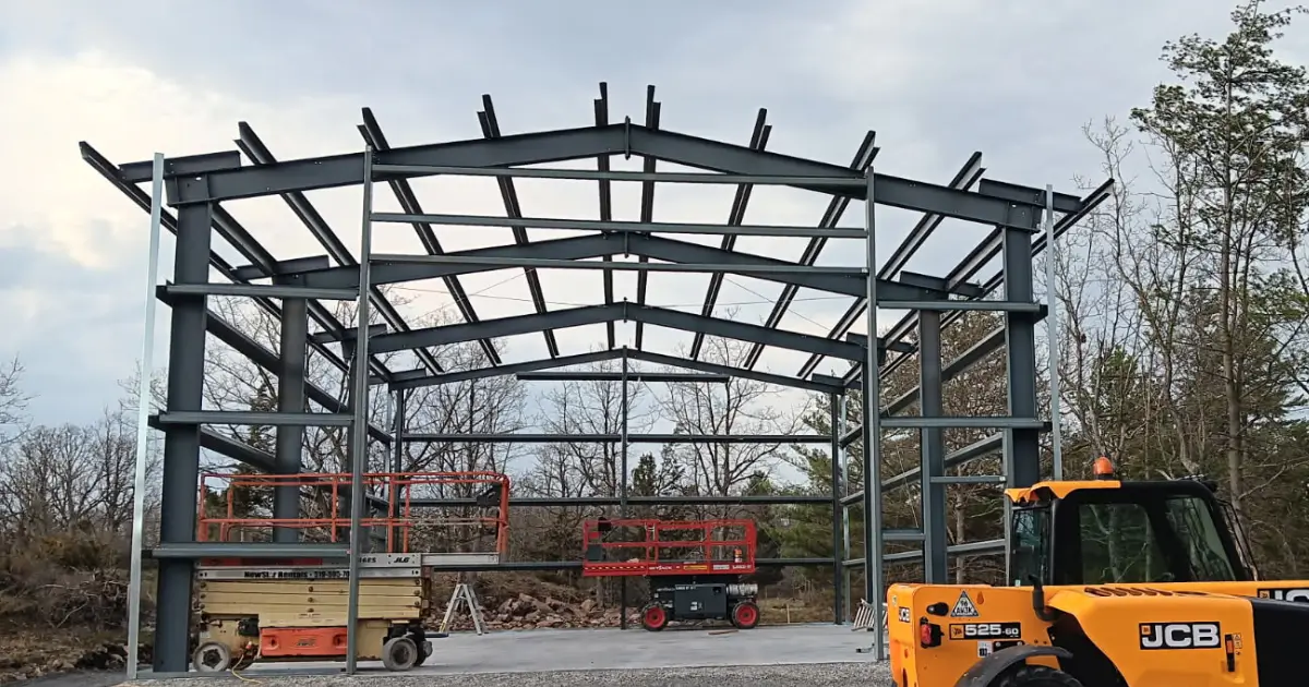 CSA A660 certified steel building structural frame under erection in Canada with engineered columns and rafters installed on concrete foundation