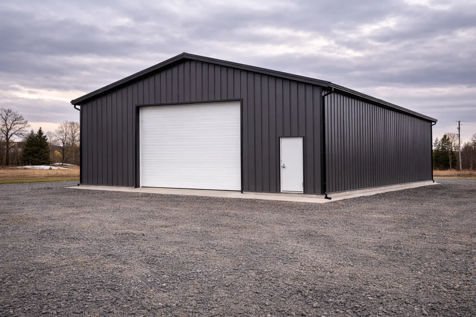 30x50x14 contractor steel workshop front 3/4 view with charcoal metal siding and overhead vehicle door on concrete slab foundation.